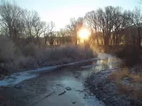 Sunrise between treen surrounding a river.